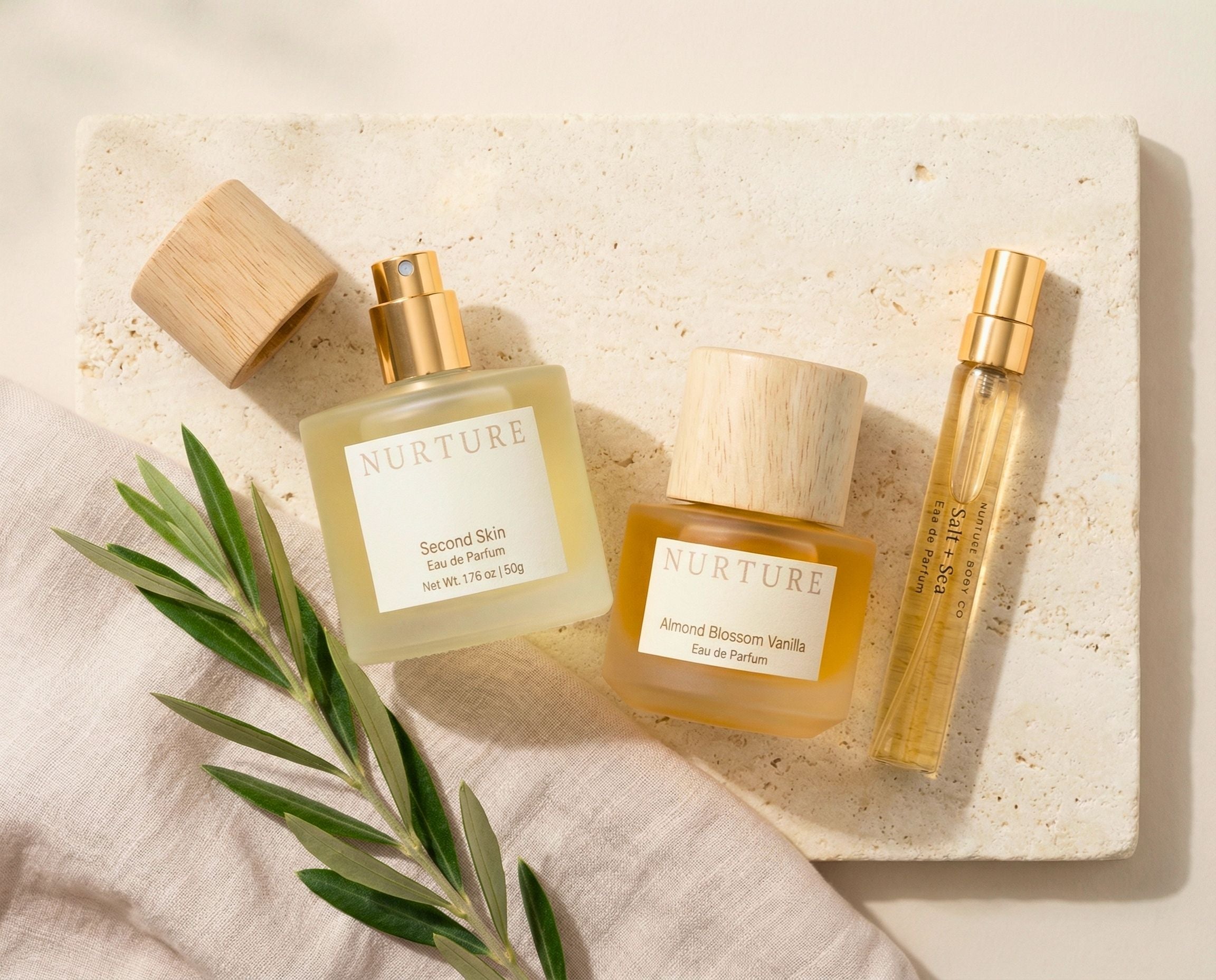 Two perfumes and an atomizer on a cream stone surface.
