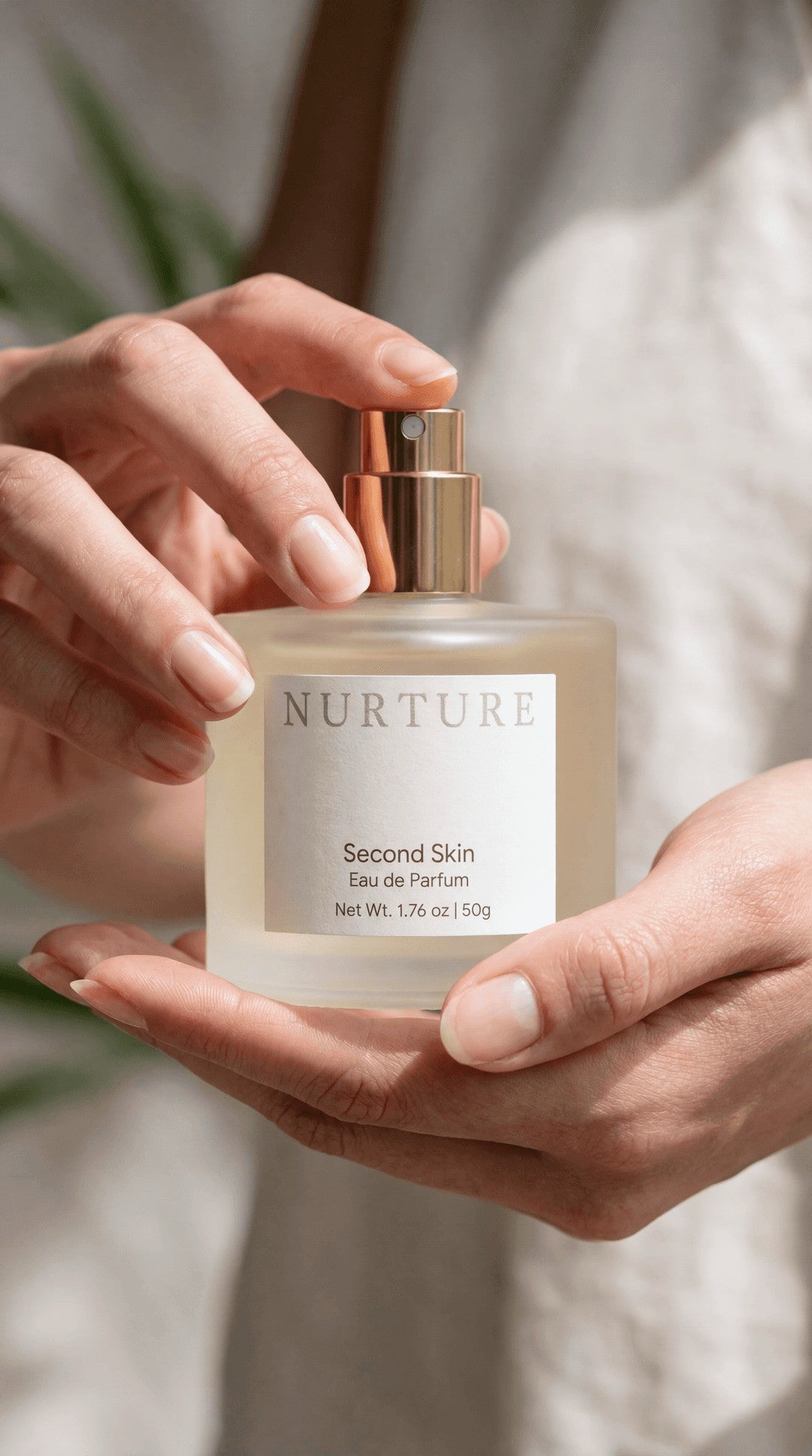 Person holding a 'Nurture Second Skin' perfume bottle with a neutral background