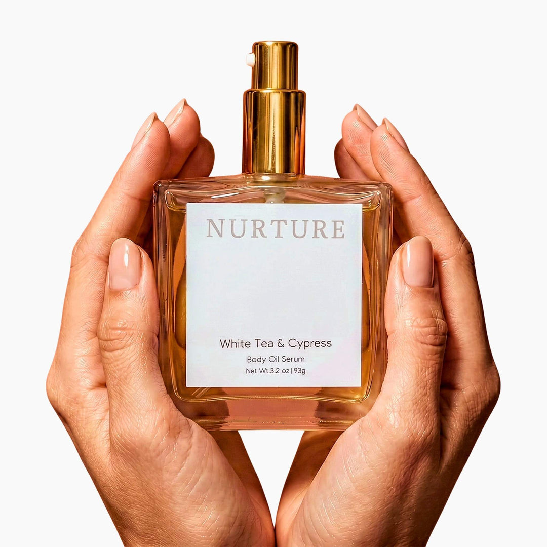 Two hands holding  a bottle of White Tea &amp; Cypress body oil.