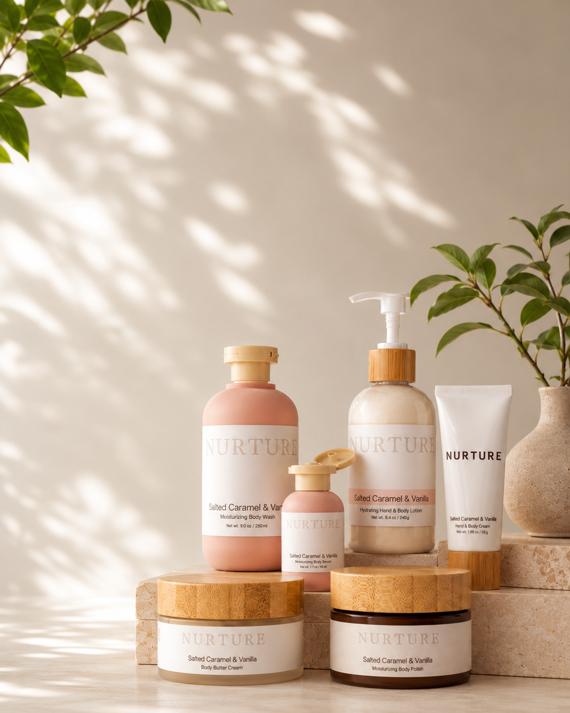 A set of NURTURE body care products arranged on stone blocks with leafy plants and dappled sunlight. The products include a large pink body wash bottle, a smaller pink bottle, a beige lotion pump bottle, a white tube, and two cream-colored jars with bamboo lids.