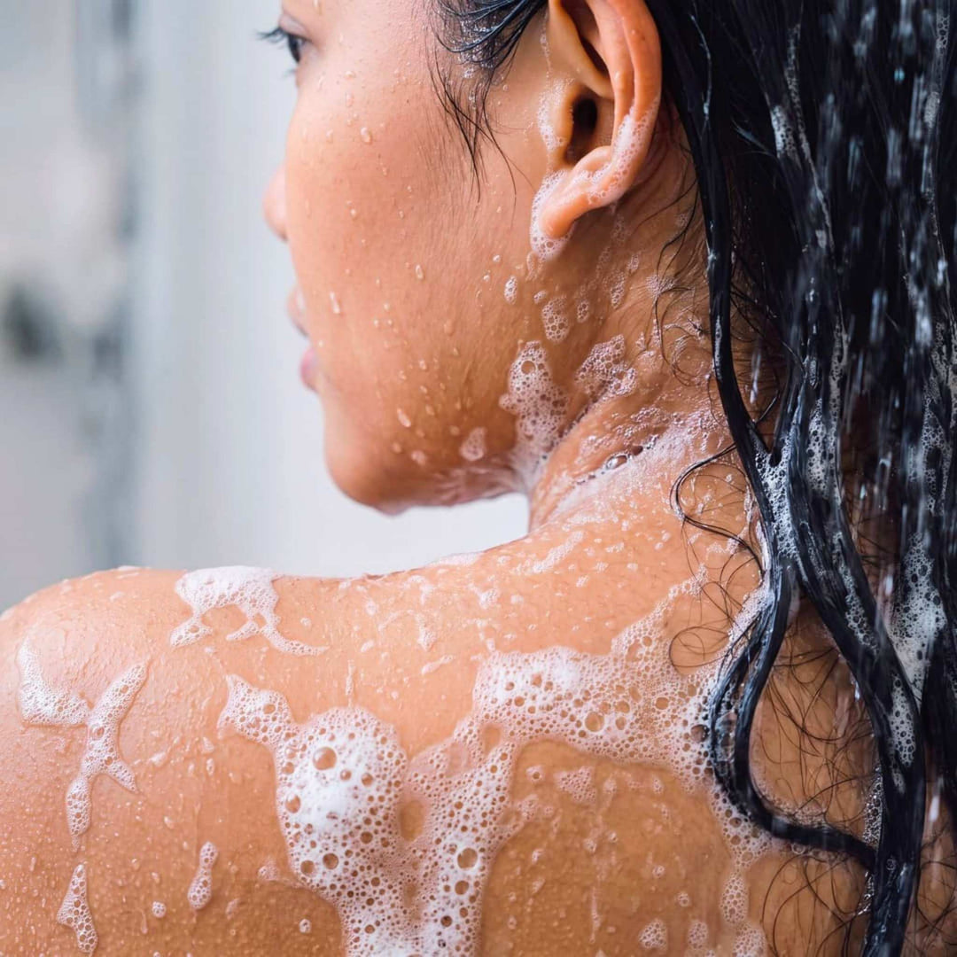 Model in shower with soap in her hair.