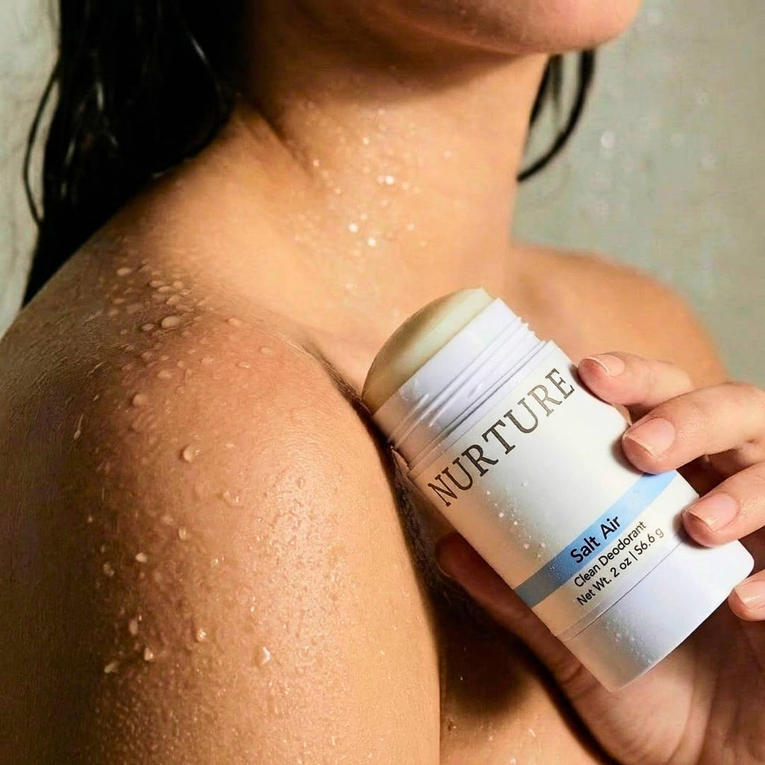 Person holding a NURTURE Salt Air Clean Deodorant next to her shoulder.