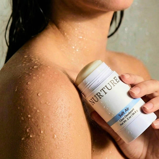 Person holding a NURTURE Salt Air Clean Deodorant next to her shoulder.
