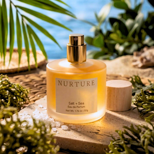 Nurture Salt + Sea perfume on a natural setting with plants and stones.