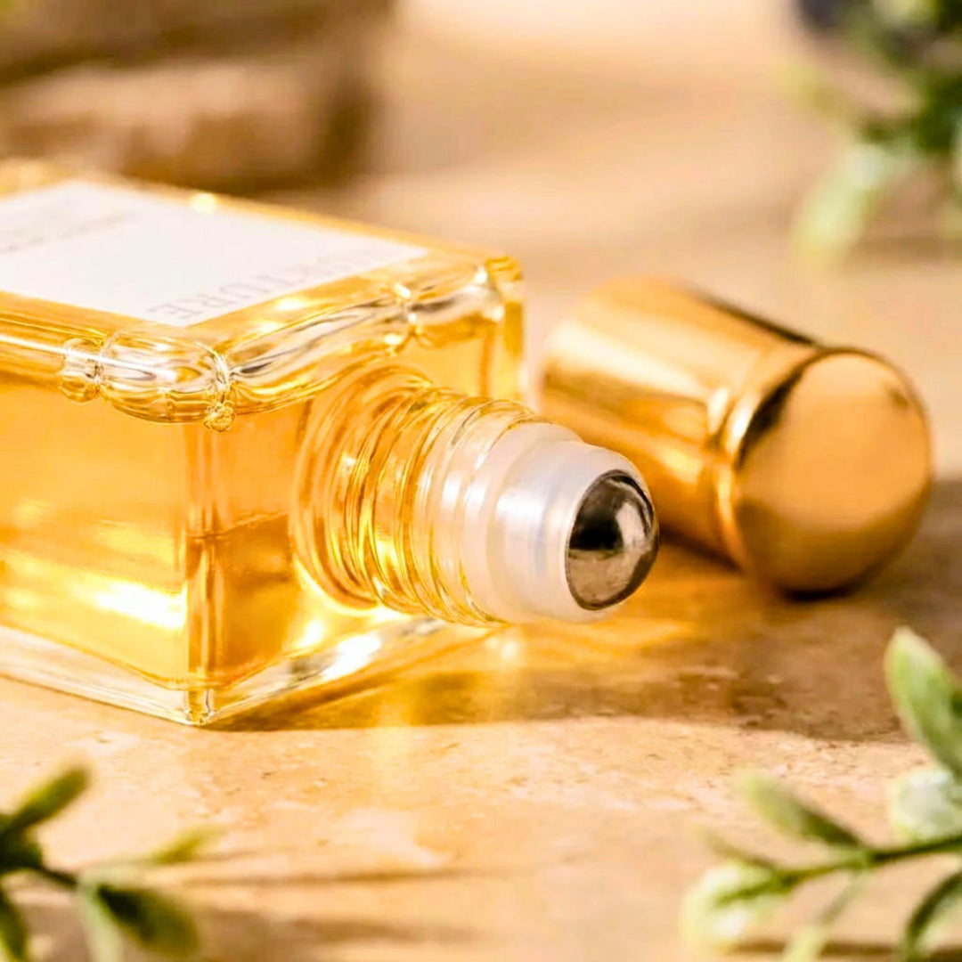 Roll-on perfume bottle with gold cap on a wooden surface with greenery