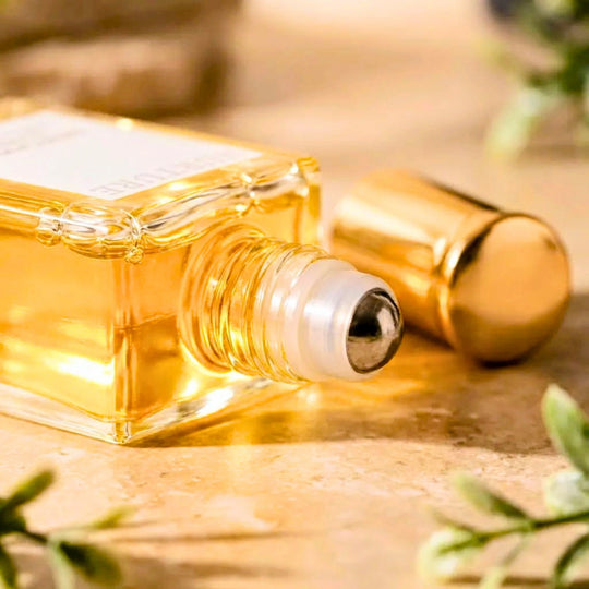 Roll-on perfume bottle with gold cap on a wooden surface with greenery