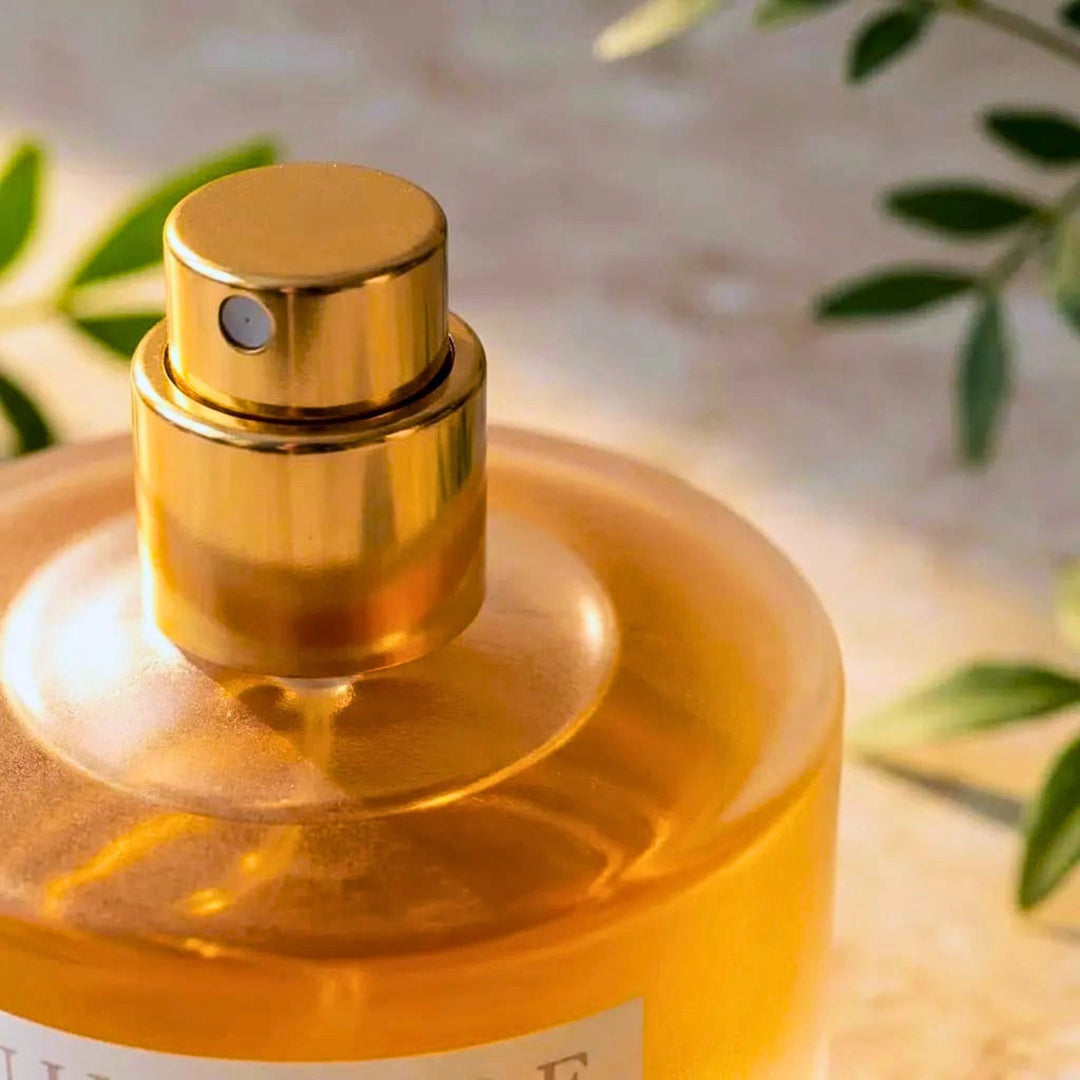 Gold perfume bottle with leaves in the background