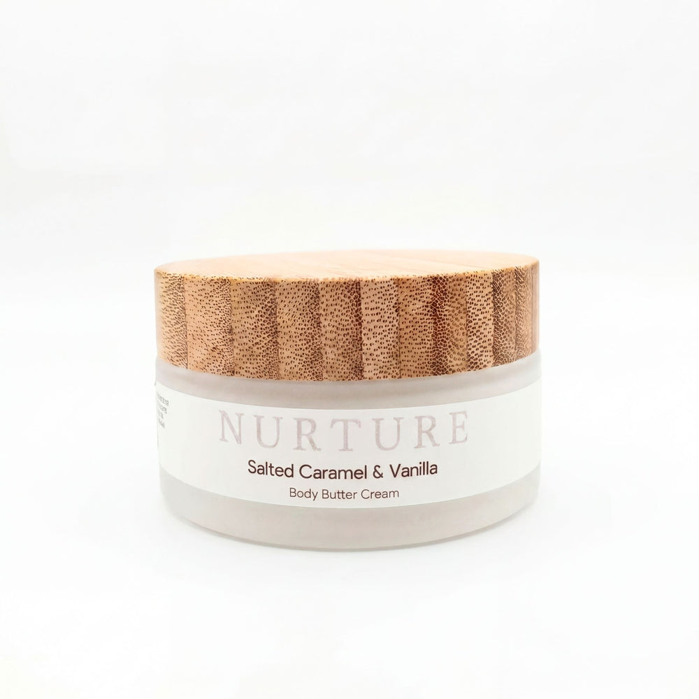 Jar of 'Nurture Salted Caramel & Vanilla Body Butter Cream' with a wooden lid on a white background