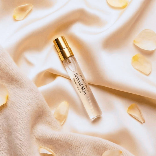 Second Skin atomizer on a soft beige fabric background with petals.