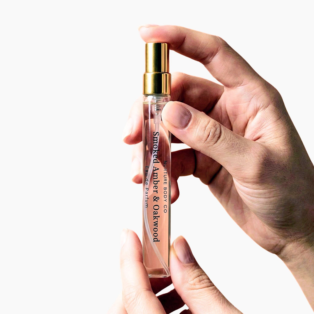 Hands holding a Smoked Amber Oakwood atomizer against a white background.
