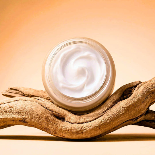 jar of body butter cream on a piece of driftwood.