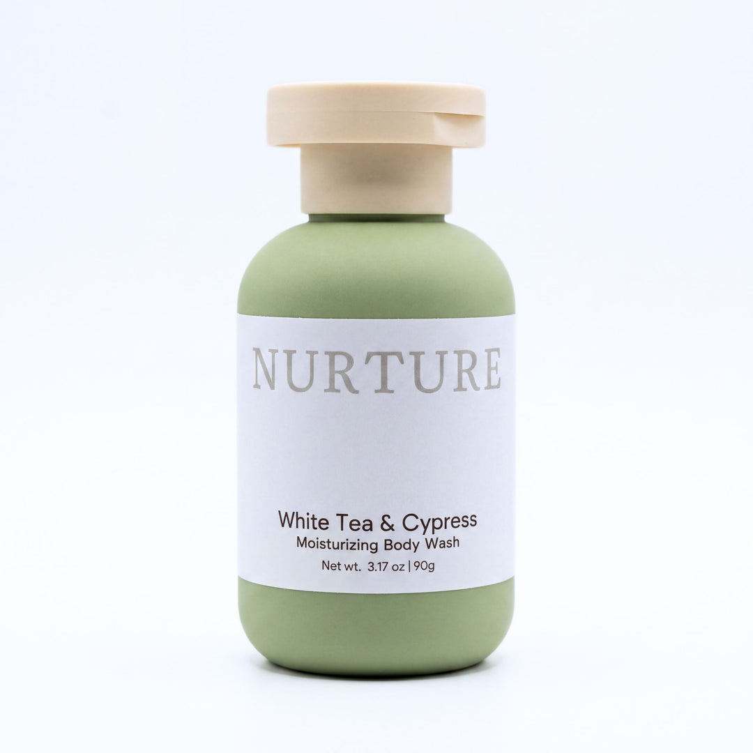 A bottle of NURTURE White Tea & Cypress Moisturizing Body Wash, featuring a sage green bottle with a beige cap and a white label, set against a clean white background.