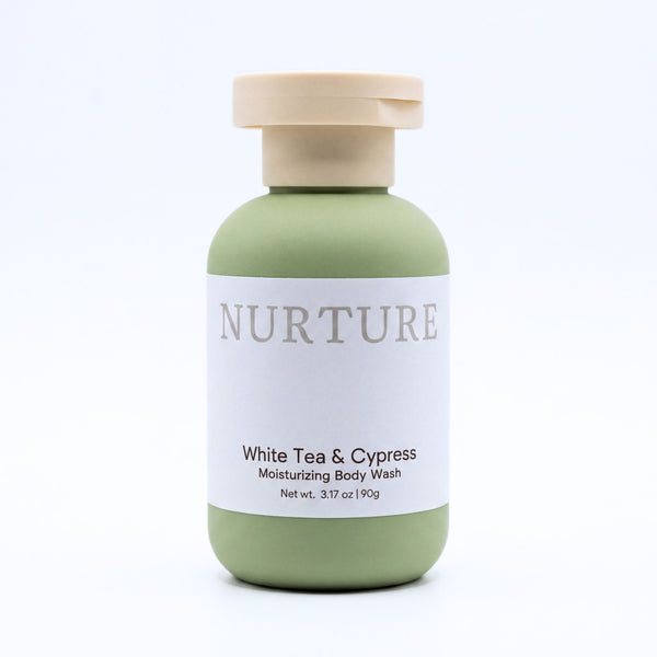 A bottle of NURTURE White Tea & Cypress Moisturizing Body Wash, featuring a sage green bottle with a beige cap and a white label, set against a clean white background.