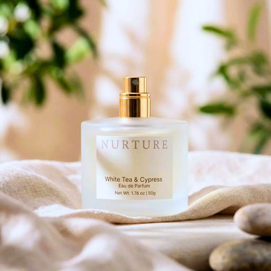 Bottle of White Tea Cypress perfume on a white linen surface.