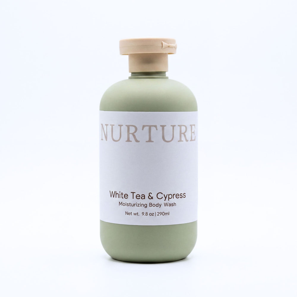 A bottle of Nurture White Tea & Cypress Moisturizing Body Wash, featuring a sage green bottle, a white label, and a beige cap, set against a plain white background.