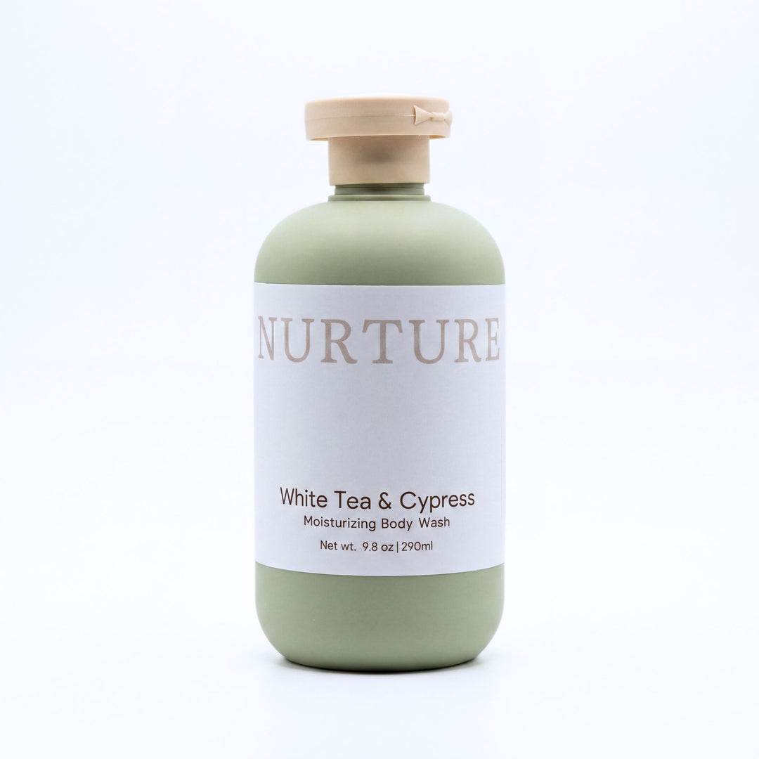 A bottle of Nurture White Tea &amp; Cypress Moisturizing Body Wash, featuring a sage green bottle, a white label, and a beige cap, set against a plain white background.