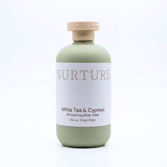 A bottle of Nurture White Tea &amp; Cypress Moisturizing Body Wash, featuring a sage green bottle, a white label, and a beige cap, set against a plain white background.