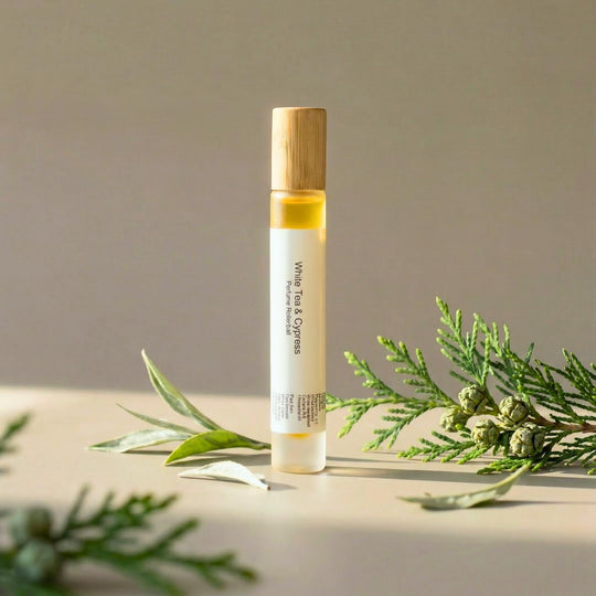 White Tea &amp; Cypress rollerball with green sprigs on a neutral background.