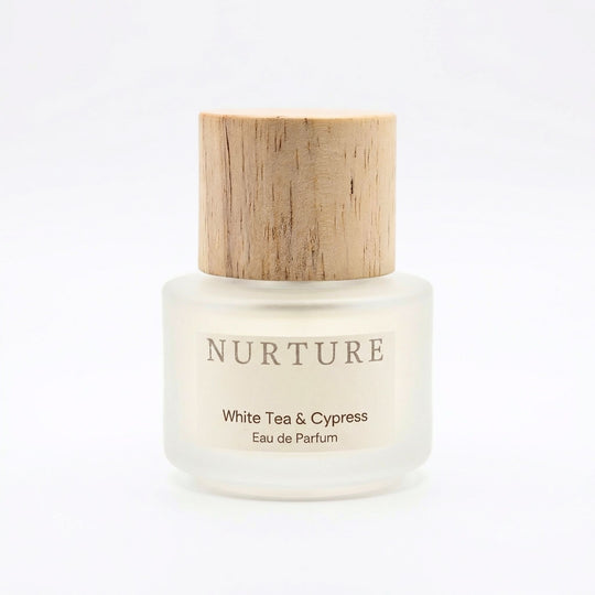 White tea and cypress perfume bottle with wooden cap on a white background