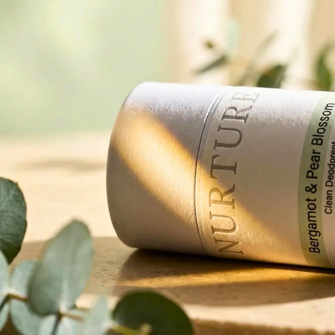 Bottle of Nurturing Clean Deodorant with green leaves in the foreground
