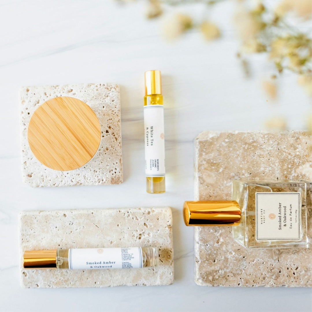 Perfume bottles and a soap on a light surface with blurred flowers in the background