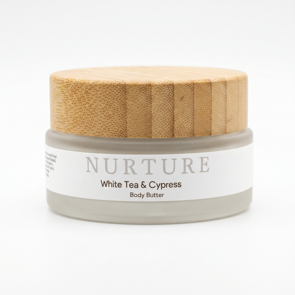 Body butter jar with wooden lid labeled 'Nurture White Tea & Cypress' on a white background