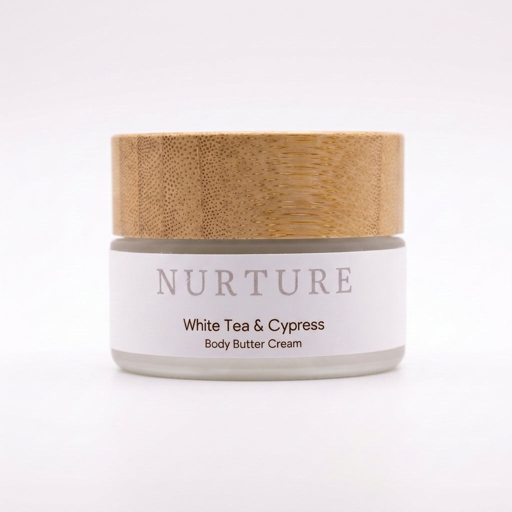 Body butter cream jar with wooden lid labeled 'Nurture White Tea & Cypress' on a white background